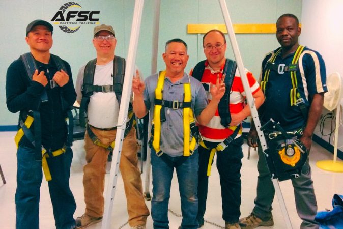 Worker inspecting fall protection harness and lanyard
